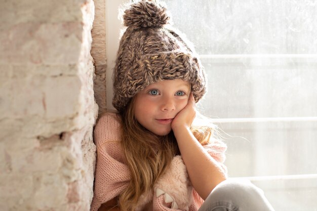 Modo di posa di modello della bambina con il cappello di inverno