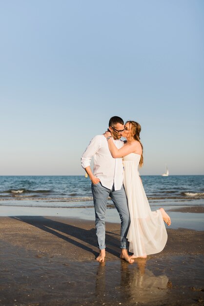 Moglie che bacia il marito vicino al mare in spiaggia