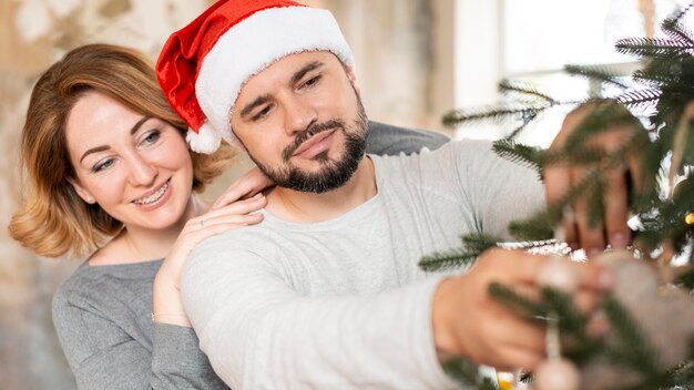 Moglie e marito decorano l'albero insieme