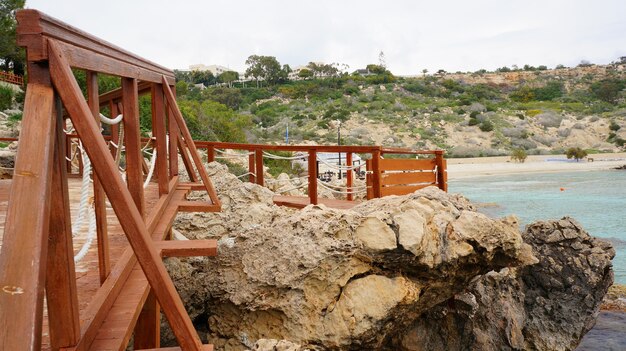 Molo in legno vicino all'oceano circondato da rocce sotto il cielo blu