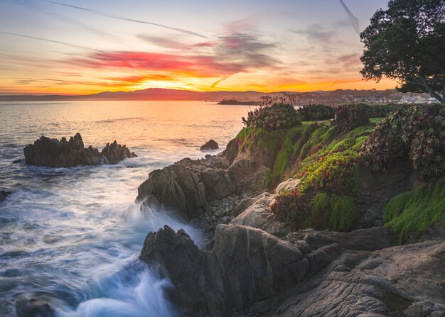 Molte formazioni rocciose ricoperte di muschio vicino al mare sotto il cielo al tramonto