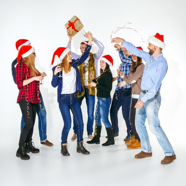 Molte giovani donne e uomini che bevono alla festa di Natale in studio bianco