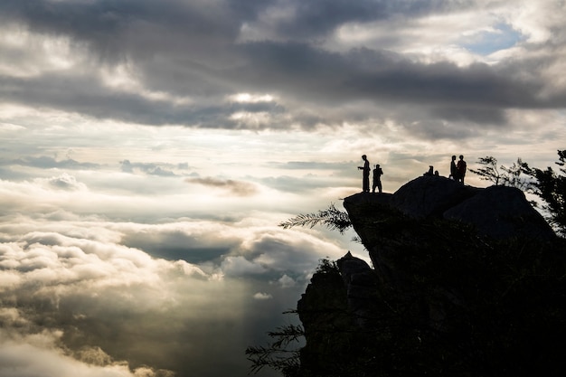 molte nuvole sull&#39;alba con persone silhouette in cima alla montagna