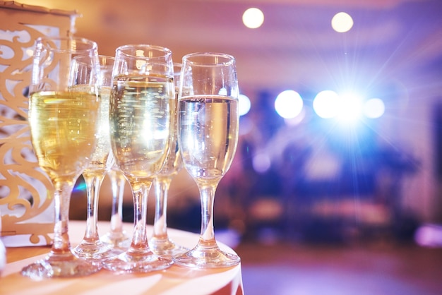 Molti bicchieri di vino in luce blu con un delizioso champagne fresco o vino bianco al bar.
