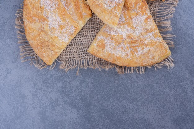 Molti pezzi di deliziosa torta con zucchero in polvere su una tela di sacco