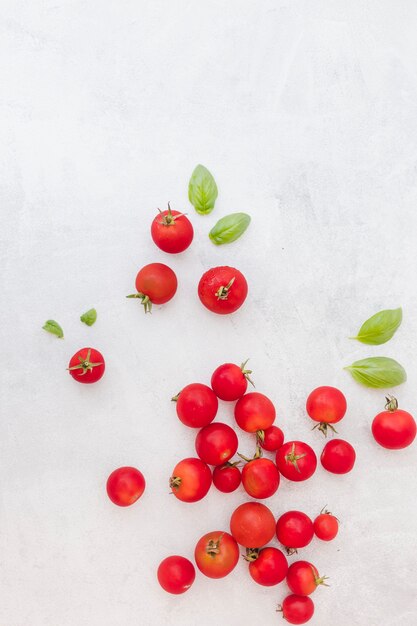 Molti pomodori rossi con foglie di basilico su sfondo con texture