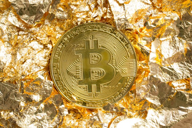 Moneta Bitcoin su pezzi di lamina d'oro intorno a sfondo decorativo