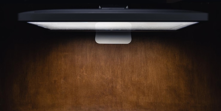 Foto gratuito monitor di computer su un tavolo di legno in una stanza buia vista dall'alto