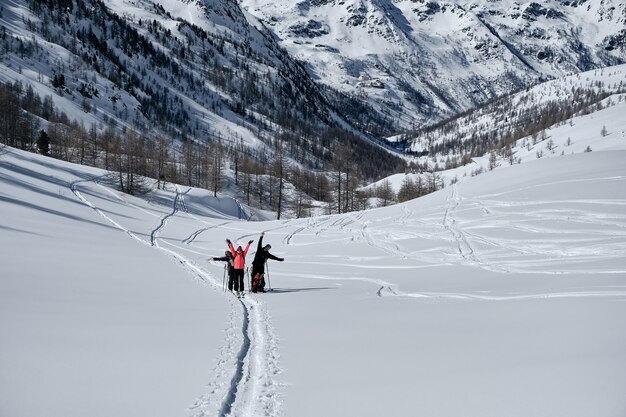 Montagna boscosa coperta di neve e gente che fa un'escursione in Col de la Lombarde