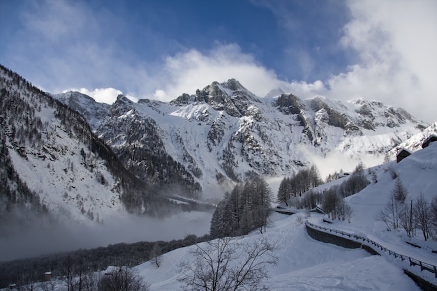 Montagna rocciosa coperta di neve e nebbia durante l'inverno con un cielo blu