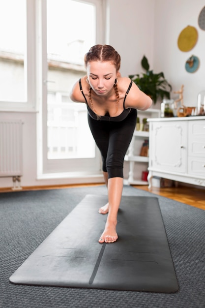 Montare la donna che fa yoga a casa vista frontale