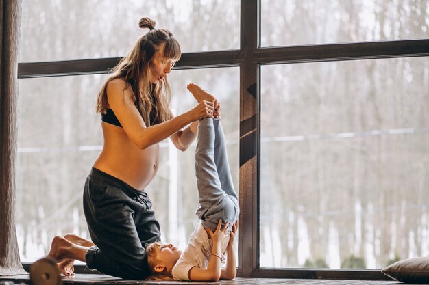 Mopther incinta che fa yoga con la piccola figlia
