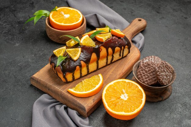 Morbide gustose torte tagliate limoni con biscotti sul tagliere di legno e asciugamano su sfondo scuro