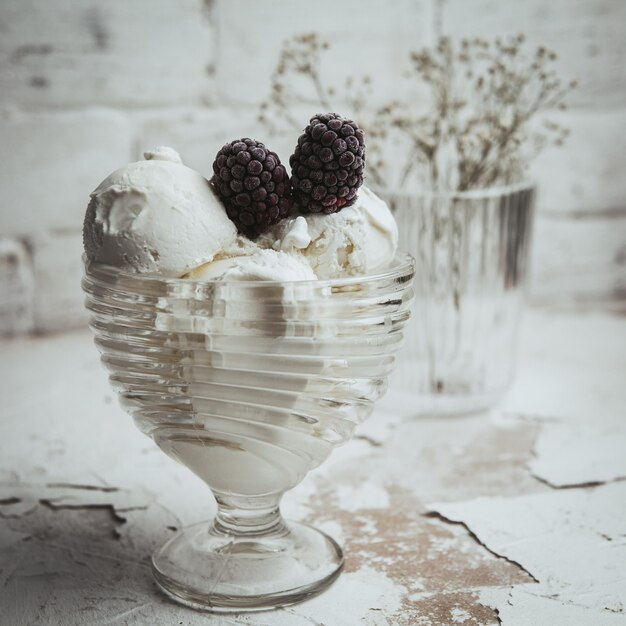 More in una tazza di vetro con il gelato su un strutturato bianco. vista laterale.