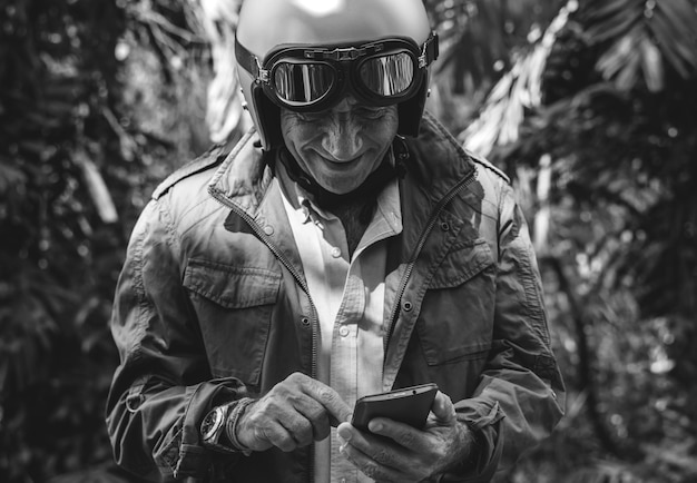 Motociclista anziano che utilizza un telefono cellulare