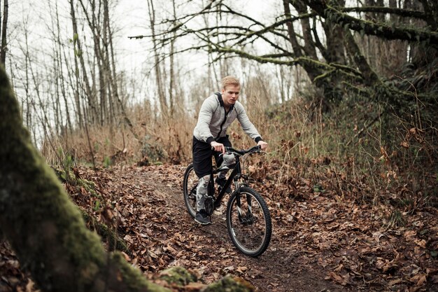 Motociclista della montagna che guida sulla bici di sport sulla traccia della foresta