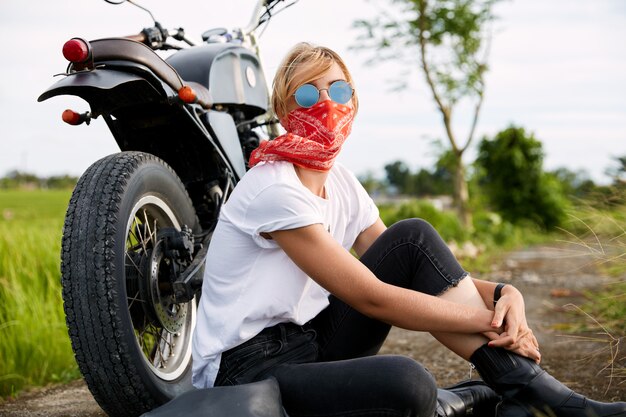 Motociclista femminile seduto accanto alla moto