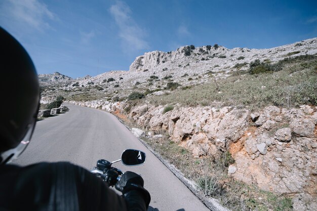 Motociclista senza volto nella campagna pietrosa