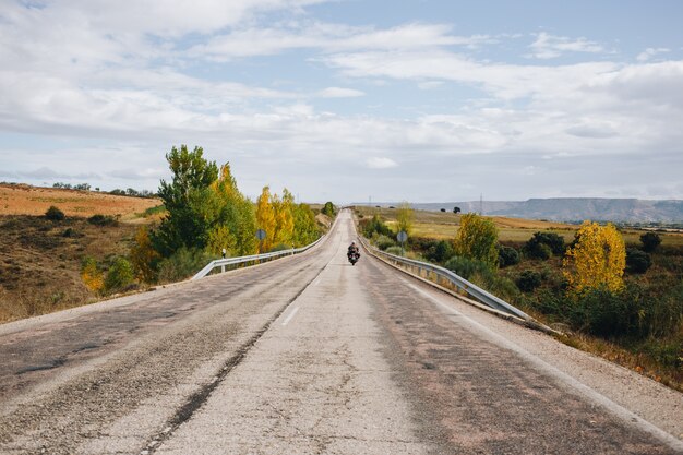 Motociclista sulla strada di campagna vuota