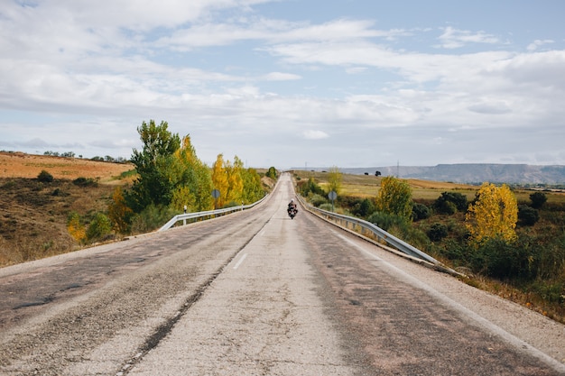 Motociclista sulla strada di campagna vuota