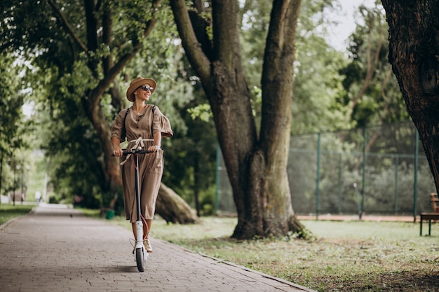 Motorino di guida della giovane donna in parco