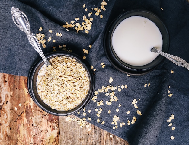 Mucchio di avena in una ciotola e bicchiere di latte