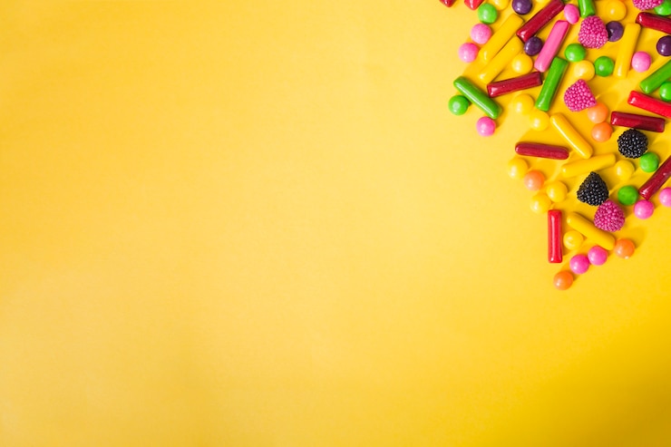 Foto gratuito mucchio di caramelle colorate su sfondo giallo