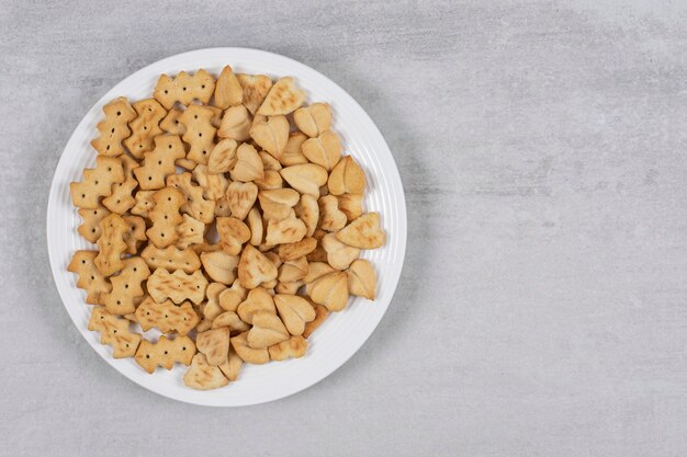 Mucchio di cracker salati sul piatto bianco.