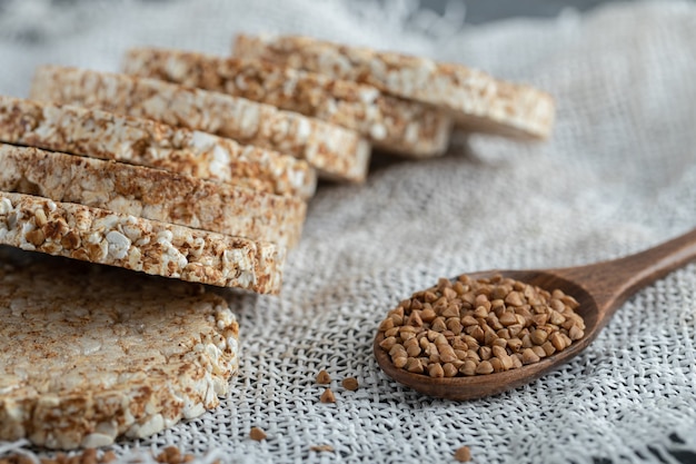 Mucchio di fette biscottate e cucchiaio di grano saraceno su tela bianca