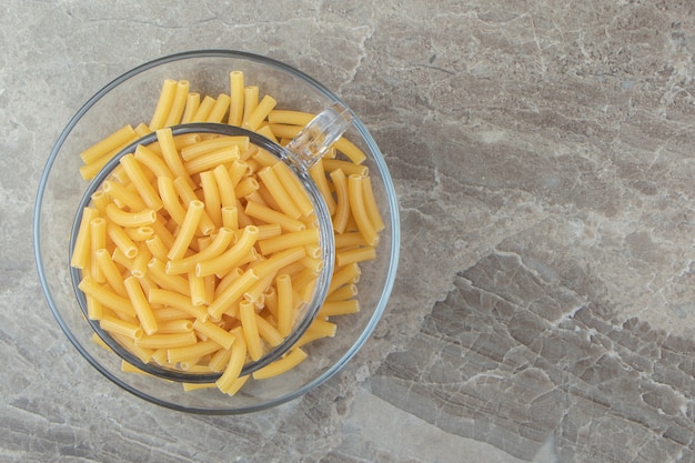 Mucchio di maccheroni crudi in tazza di vetro.