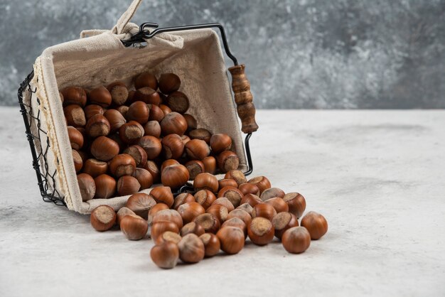 Mucchio di nocciole sgusciate organiche dal cestello sul tavolo di marmo.