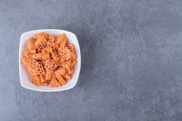 Mucchio di pasta a forma di cuore in ciotola bianca.