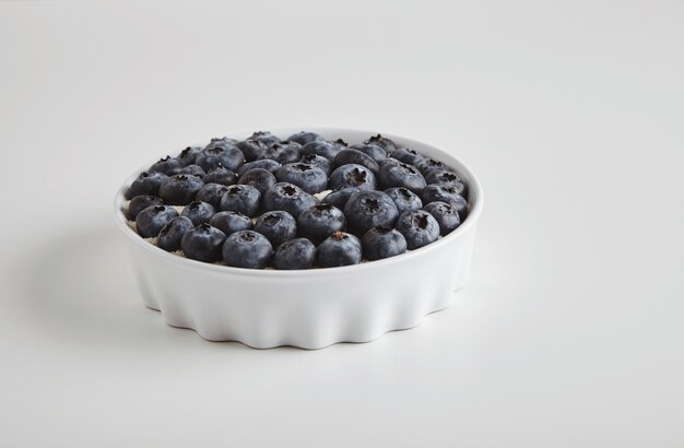Mucchio di superfood organico antiossidante mirtillo nel concetto di ciotola di ceramica per una sana alimentazione e nutrizione isolato sul tavolo bianco