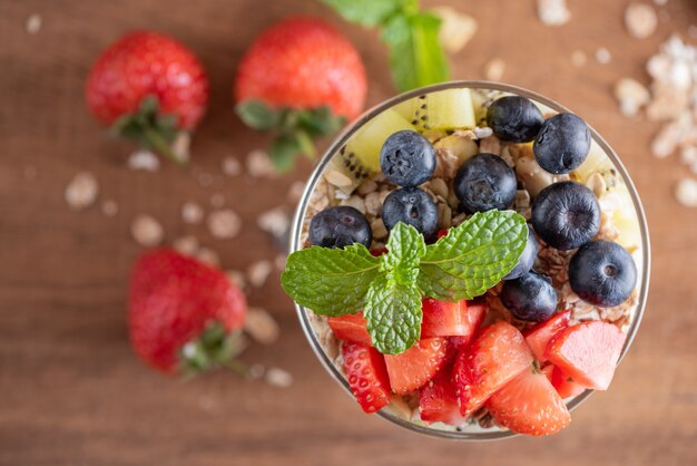 Muesli fatto in casa, ciotola di muesli d'avena con yogurt, mirtilli freschi, gelso, fragole, kiwi, menta e noci per una sana colazione, copia spazio. Concetto di colazione sana. Mangiare pulito.