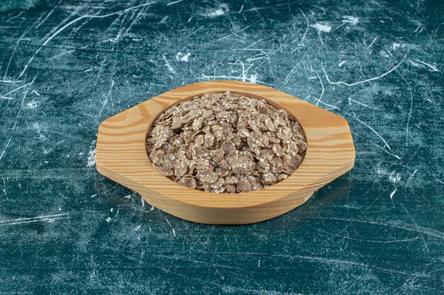 Muesli organici e fatti in casa in un piatto di legno, sullo sfondo blu. Foto di alta qualità