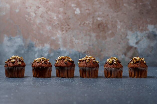 Muffin al cioccolato e noci con una tazza di caffè con noci sulla superficie scura