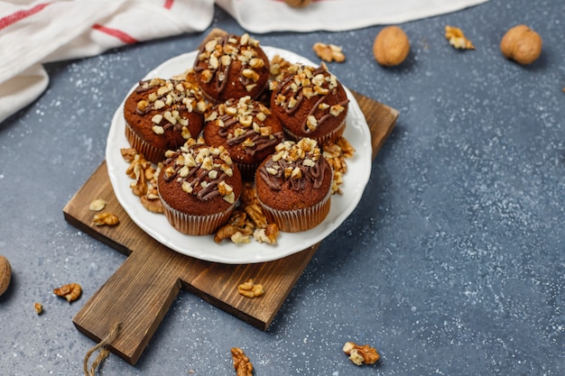 Muffin al cioccolato e noci con una tazza di caffè con noci sulla superficie scura