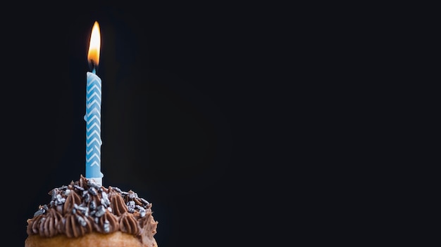 Muffin saporito di compleanno su fondo nero con lo spazio della copia