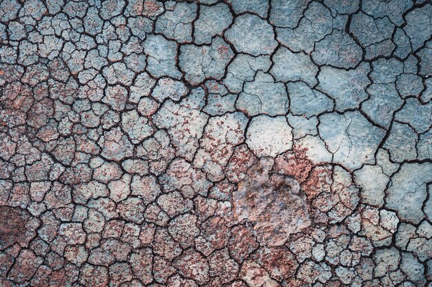 Muro blu incrinato con sabbia rossa su di esso