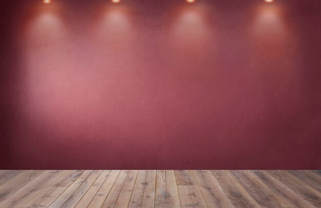 Muro rosso con una fila di faretti in una stanza vuota