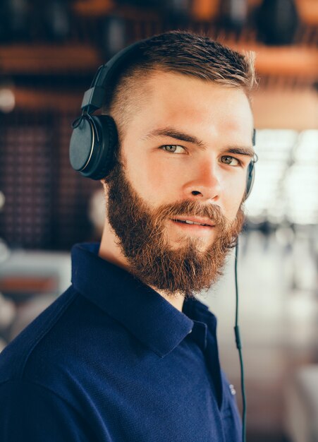 Musica d&#39;ascolto del giovane in cuffie, facendo uso dello smartphone, ritratto all&#39;aperto dei pantaloni a vita bassa