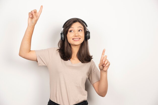 Musica d'ascolto della donna graziosa con le sue cuffie su priorità bassa bianca.