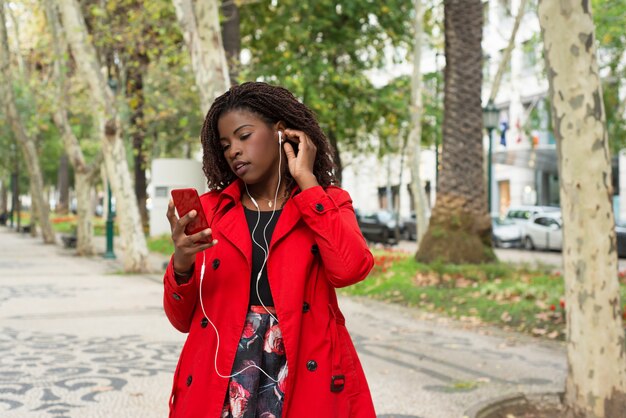 Musica d'ascolto della donna tramite telefono cellulare in parco