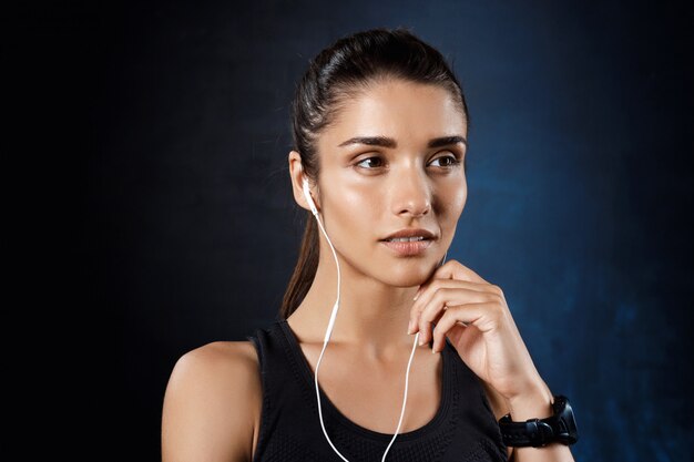 Musica d'ascolto della giovane bella ragazza allegra sopra la parete scura.