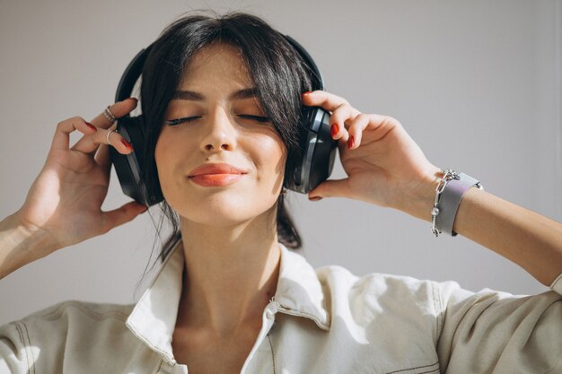 Musica d'ascolto della giovane donna graziosa sulle cuffie senza fili