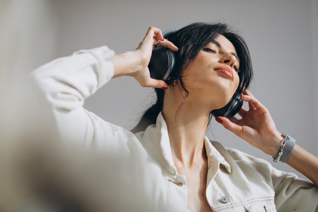 Musica d'ascolto della giovane donna graziosa sulle cuffie senza fili