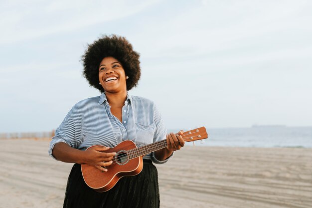 Musicista afroamericano che gioca ukulele in spiaggia