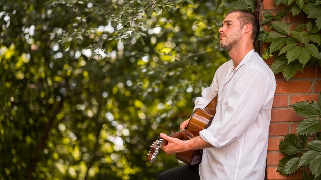 Musicista di lato che suona la chitarra acustica all'aperto