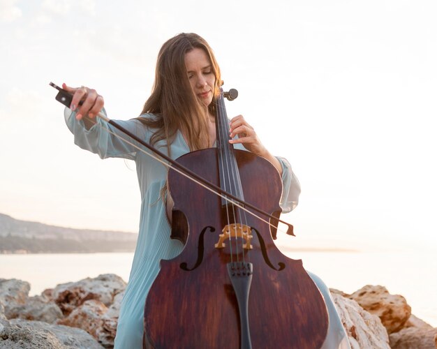 Musicista femminile che gioca violoncello all'aperto