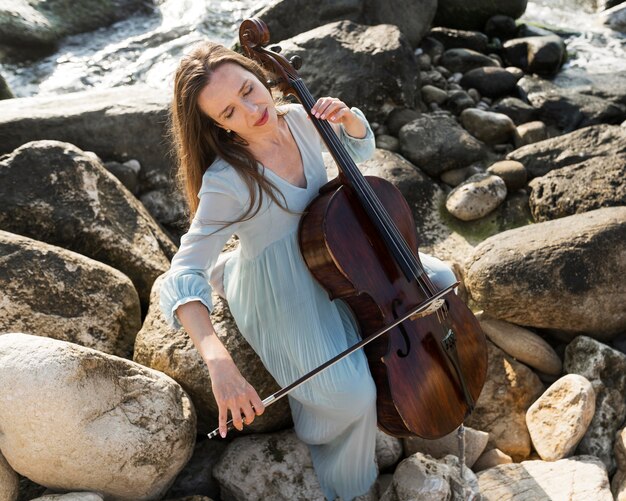 Musicista femminile che suona il violoncello in riva al mare